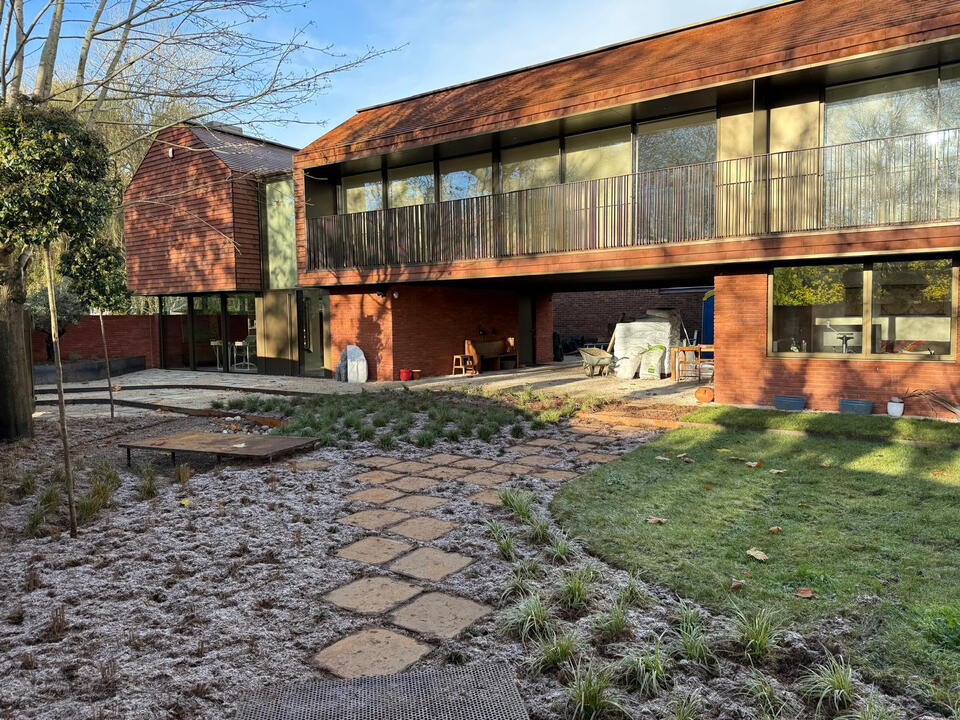 Completed garden in Marlow featuring layered planting, Corten steel walkway and bridge over a seasonal pond, and permeable gravel paths -a sustainable landscape combining flood management with rustic elegance and contemporary design